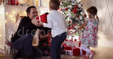 快乐的父母用装饰好的树把圣诞礼物送给他们的孩子。